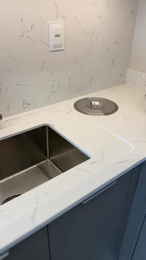 Bancada de quartzo branco com cuba de inox embutida.