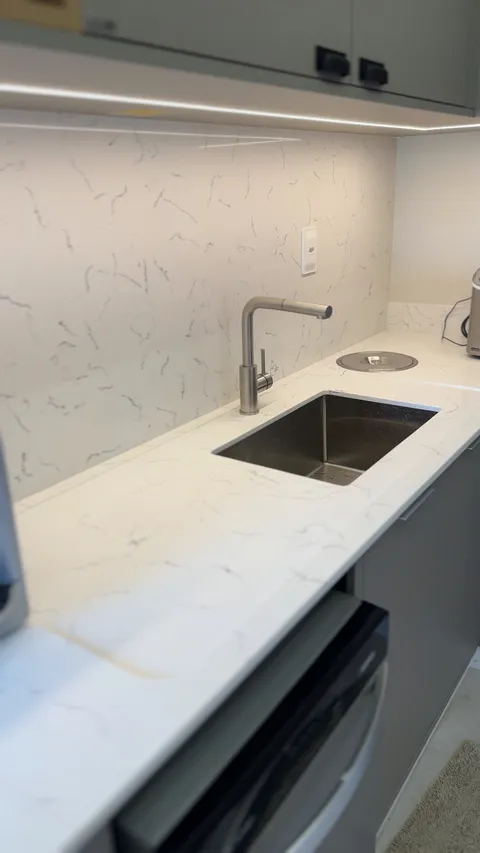 Bancada de quartzo branco com rodabanca e torneira.