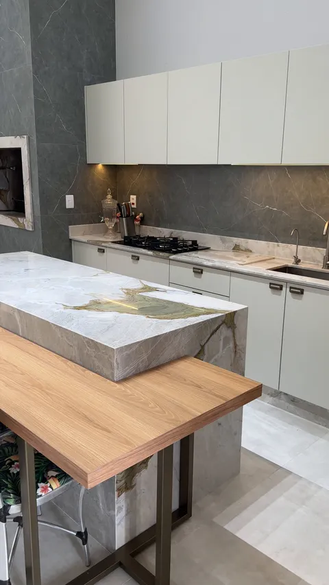 Cozinha com ilha em quartzito e mesa de madeira acoplada.
