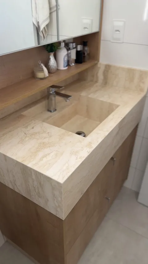 Lavabo com cuba esculpida na própria pedra, em travertino.